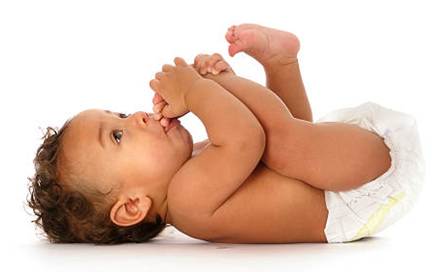Baby lying on back holding feet and sucking toes.
