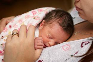 Newborn baby peacefully sleeping on a caregiver's chest.