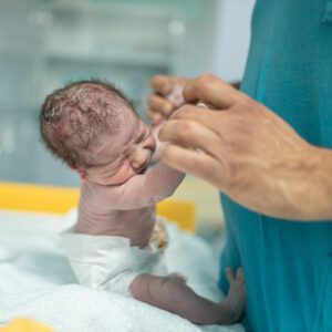Infant grasping adult fingers in hospital