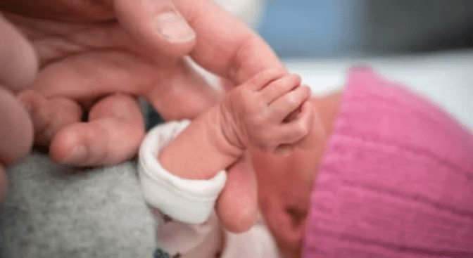 Tiny hand gripping a finger