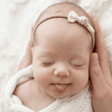 Sleeping baby with a soft headband and gentle smile.